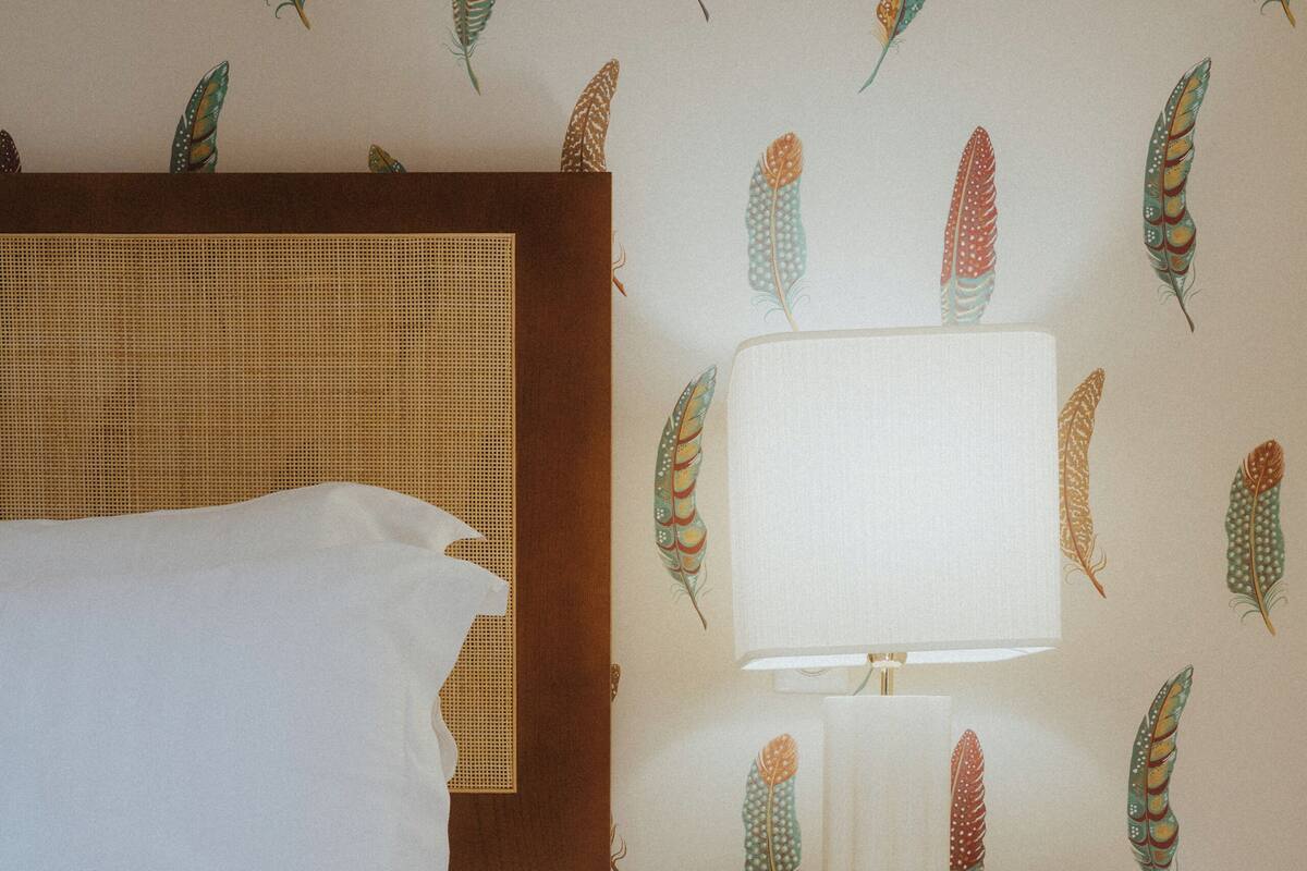 A neatly made bed with white bedding, a bedside lamp, and a nightstand with drawers.