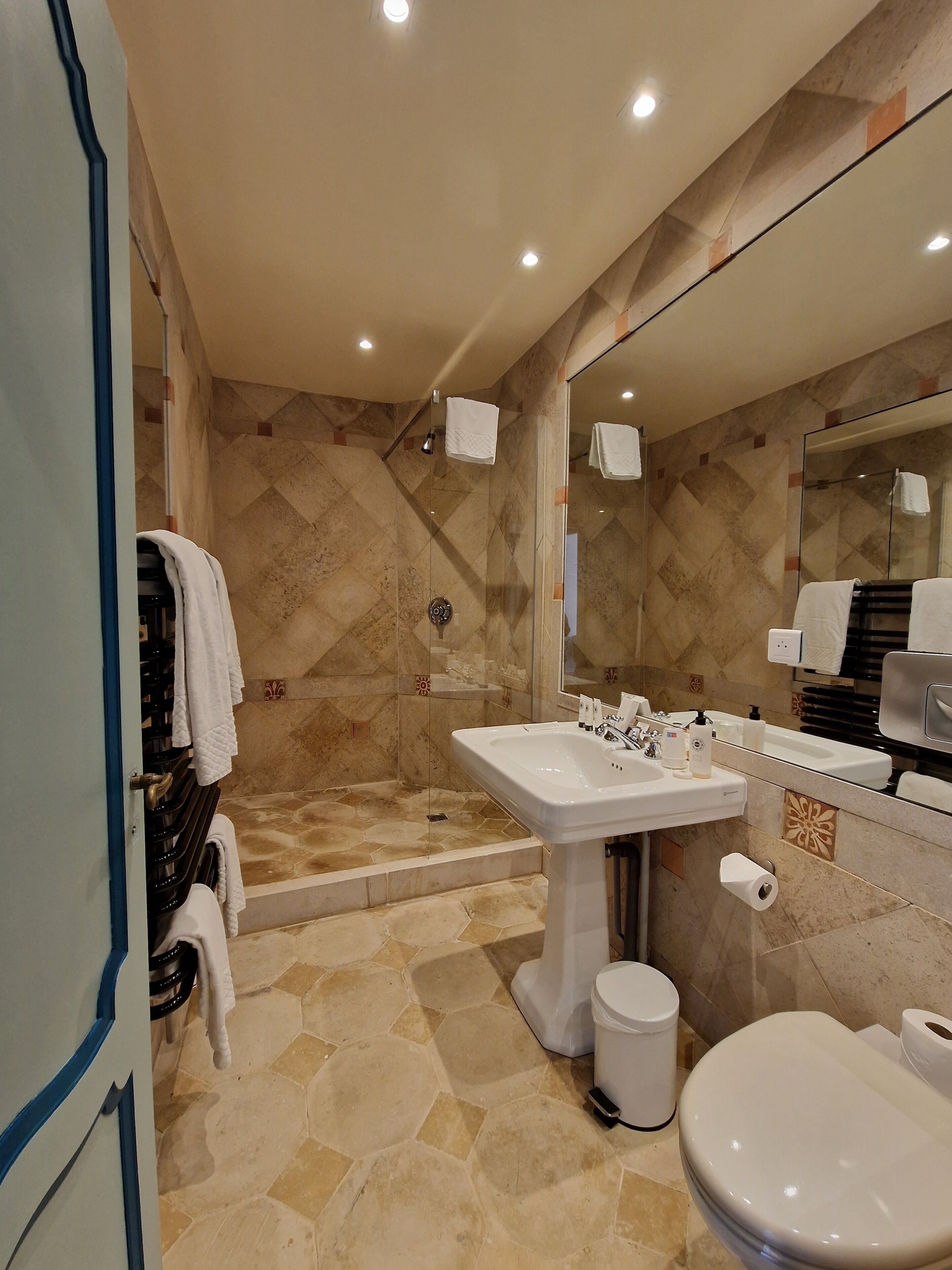 A modern bathroom with a shower, sink, toilet, and a large mirror.
