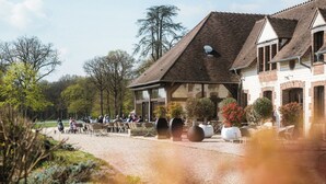 A building with a sloped roof, outdoor seating, and a gravel path. - Domaine Et Golf Du Roncemay (Chassy)