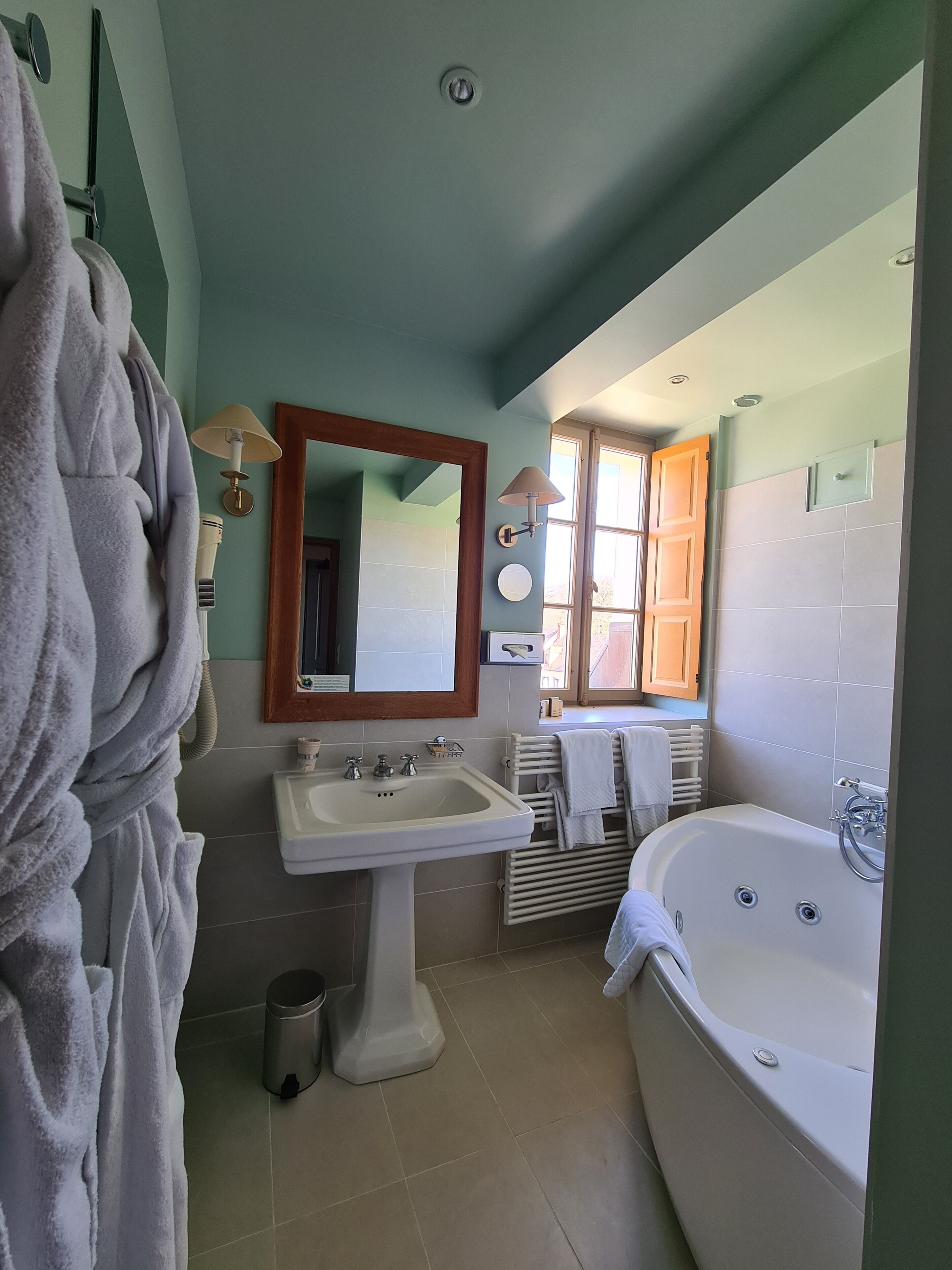 Une salle de bain équipée d’un lavabo, d’un miroir, d’un porte-serviettes et d’une baignoire.