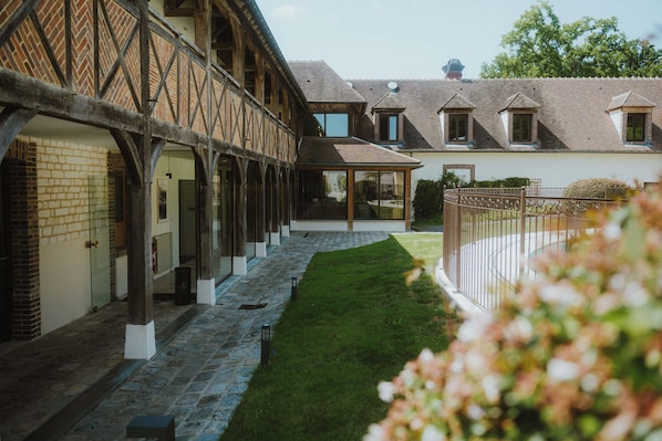 Ein Innenhof mit überdachtem Gang, einem Backsteinhaus und einem weißen Gebäude mit zahlreichen Fenstern.