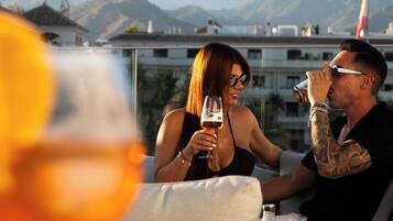 A couple sitting at an outdoor table with a city view and mountains in the background.