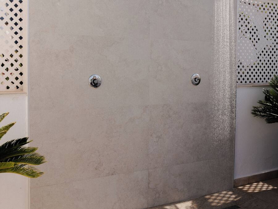 Ducha exterior moderna con pared texturizada, cabezal de ducha de lluvia y llave de control.