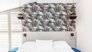 Une chambre avec un lit, un mur orné d’un motif floral et deux lampes suspendues.