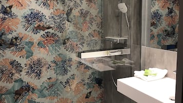 A modern bathroom with a shower, a glass-enclosed vanity, and a floral-patterned wall.