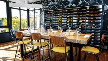 A restaurant with a long wooden table set for dining, surrounded by chairs with yellow cushions.