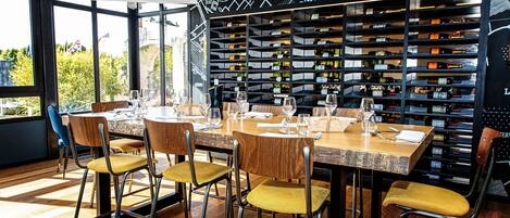 A restaurant with a long wooden table set for dining, surrounded by chairs with yellow cushions.