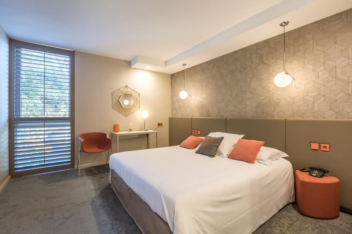 Une chambre d’hôtel moderne, dotée d’un grand lit, d’un bureau et d’une chaise.