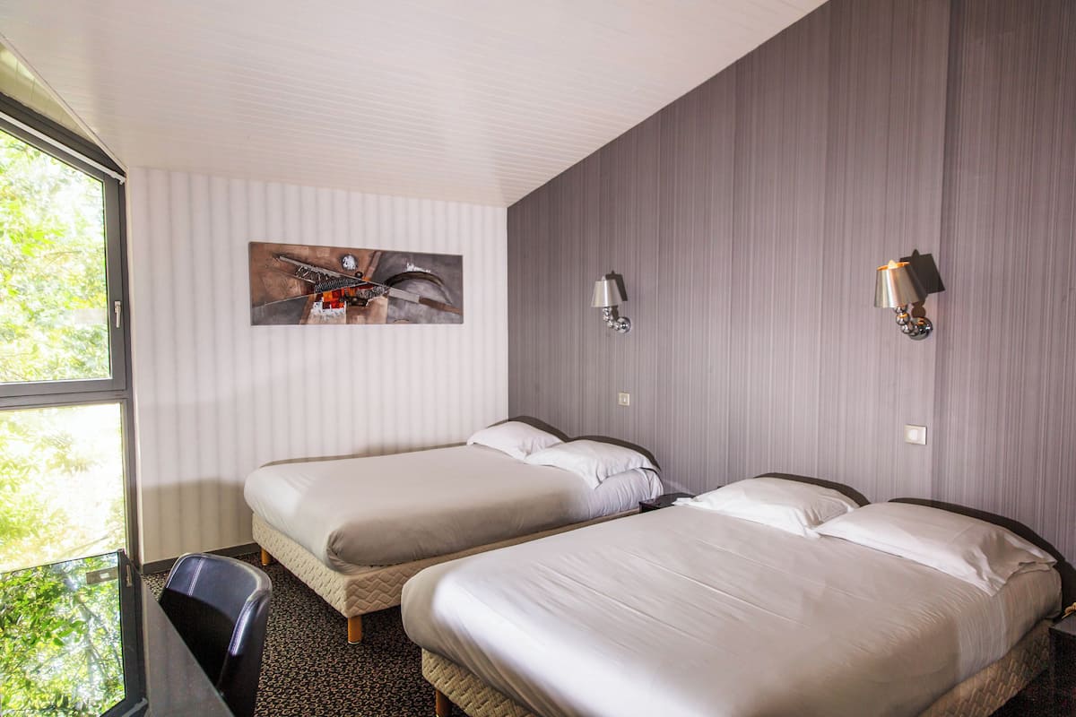 Une chambre d’hôtel avec deux lits, un bureau et une fenêtre.