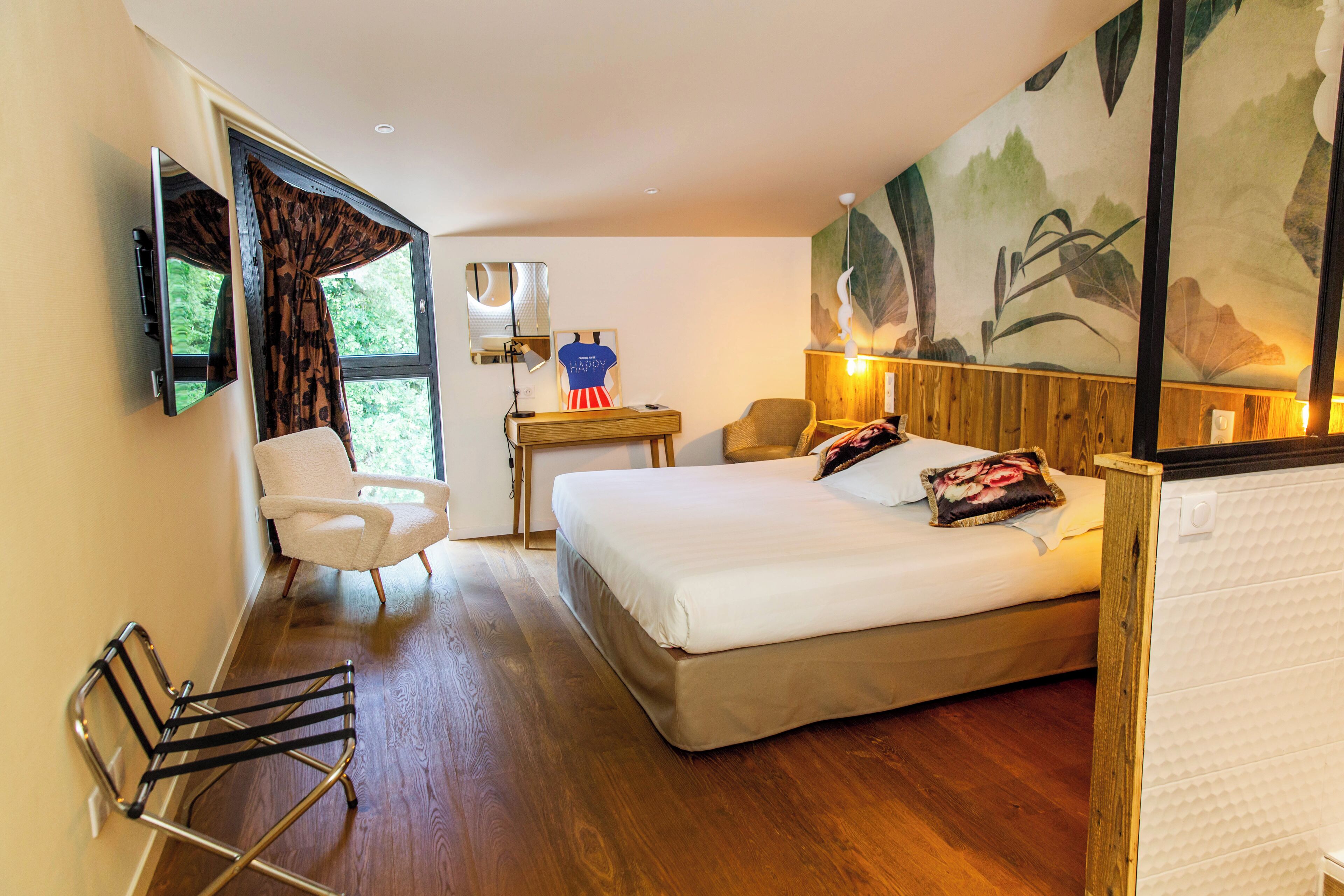 A hotel room with a bed, a desk, a chair, a TV, and a window with curtains.