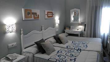 Habitación de hotel con dos camas, una mesita de noche, una lámpara, un espejo y obras de arte en las paredes.