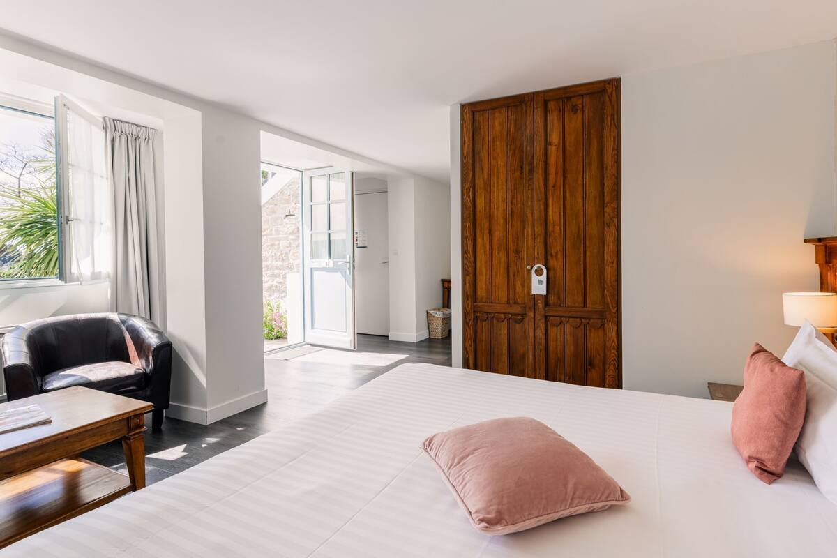Una habitación de hotel con una cama grande, un armario de madera, un escritorio y una silla.