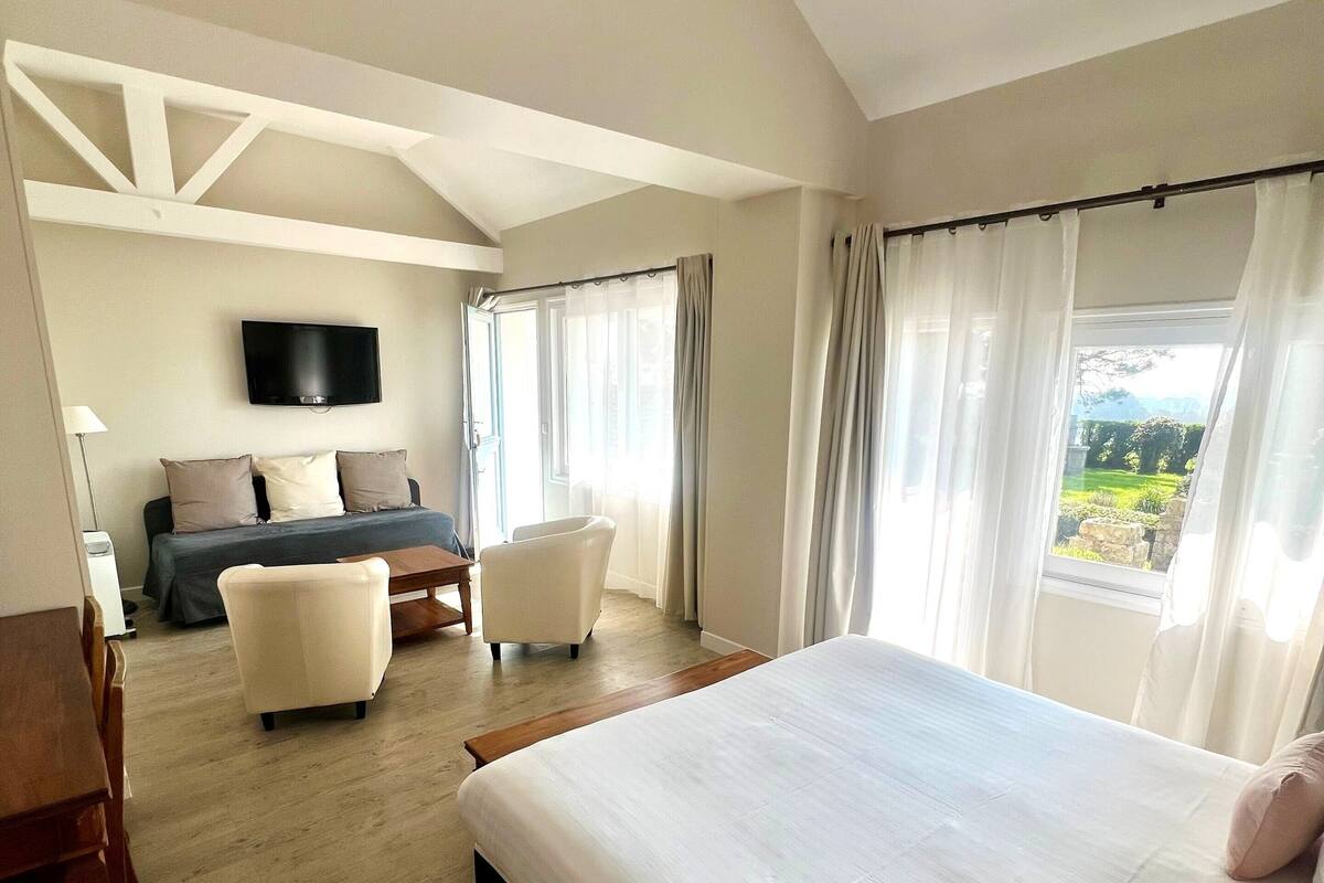 Habitación de hotel con una cama grande, un escritorio, una silla, un televisor en la pared y vistas al exterior.