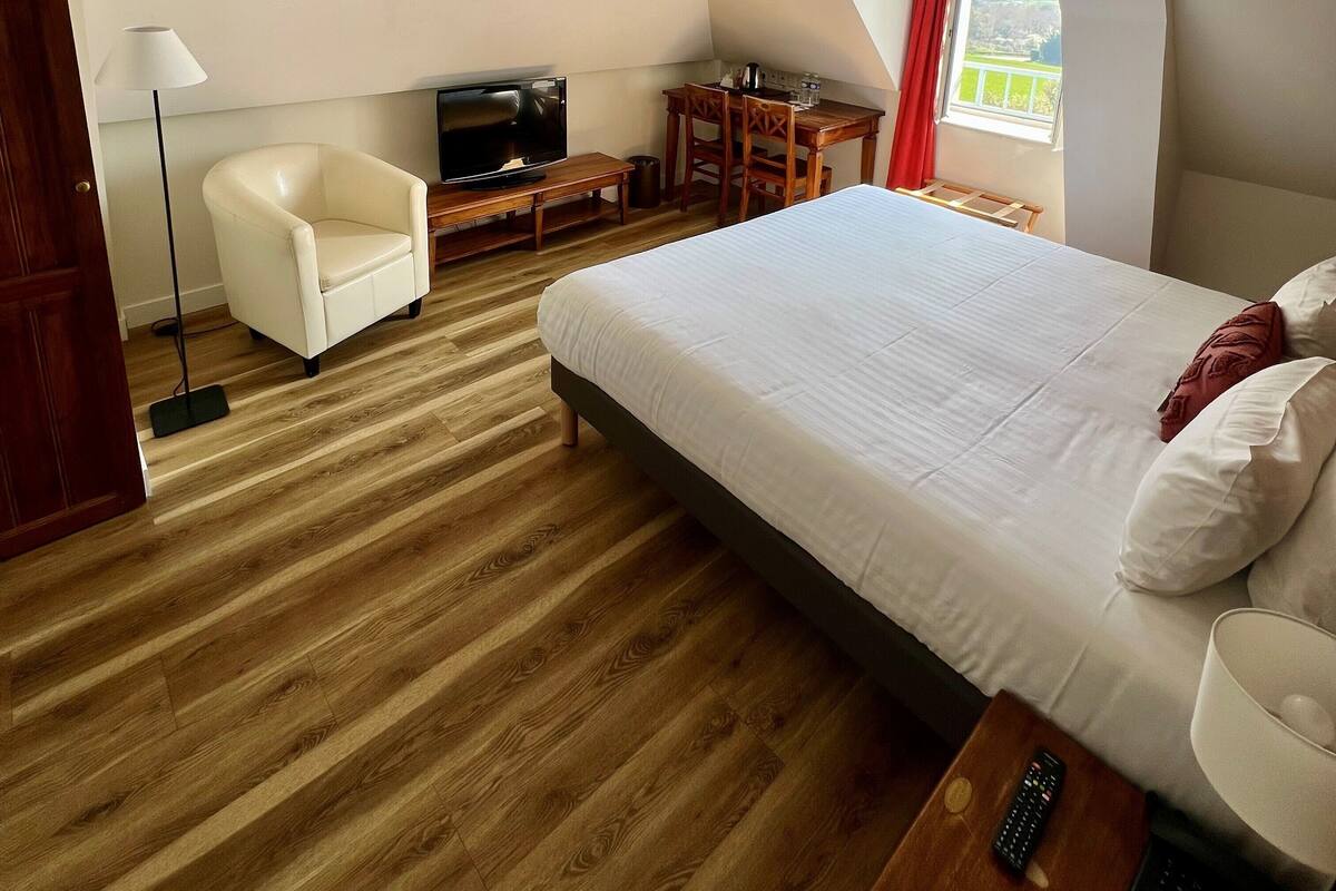Habitación de hotel con cama, televisor, escritorio, silla y ventana con vistas.