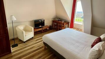 Hotelkamer met een bed, televisie, bureau, stoel en raam met uitzicht.