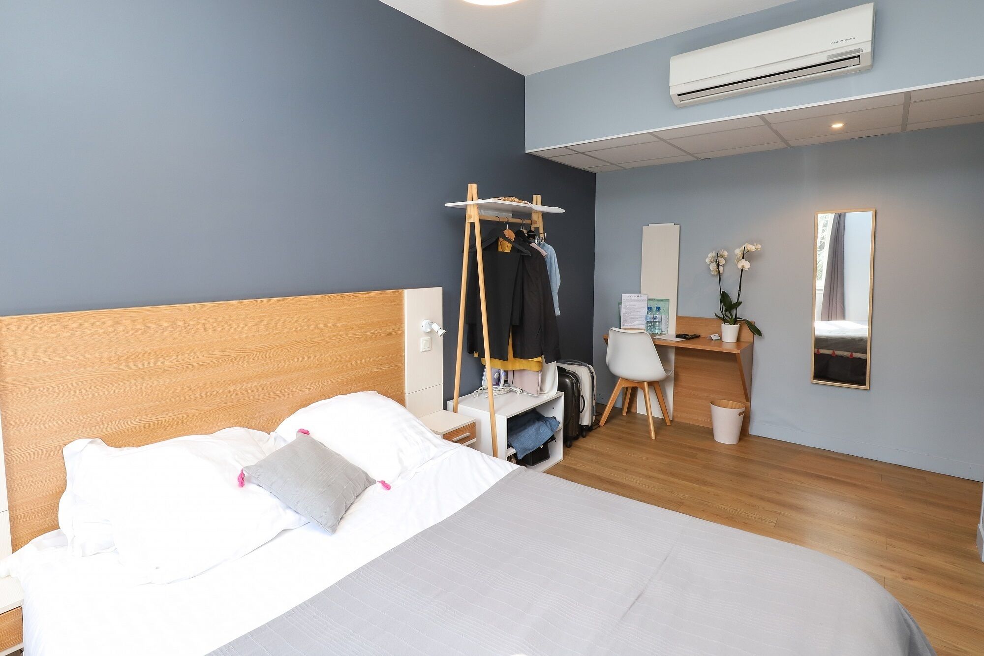 Une chambre d’hôtel équipée d’un lit, d’un bureau, d’un climatiseur et d’un miroir.