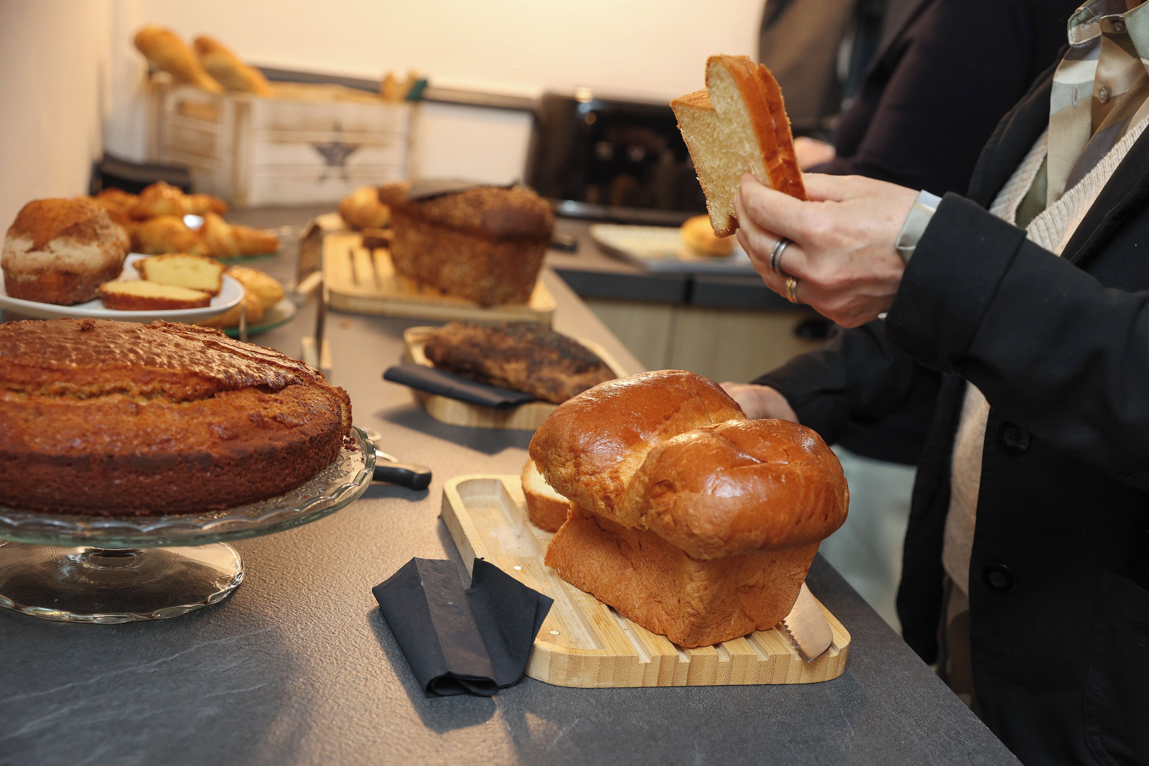A variety of baked goods on display, including a cake, muffins, and bread, suggesting a bakery or cafe setting.