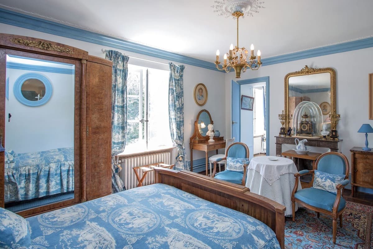 Une chambre à coucher avec un grand lit, une commode, une chaise, une table et un miroir.