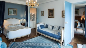 A bedroom with a bed, a sofa, a chandelier, and framed pictures on the walls. - Château de la Rue (Suevres)