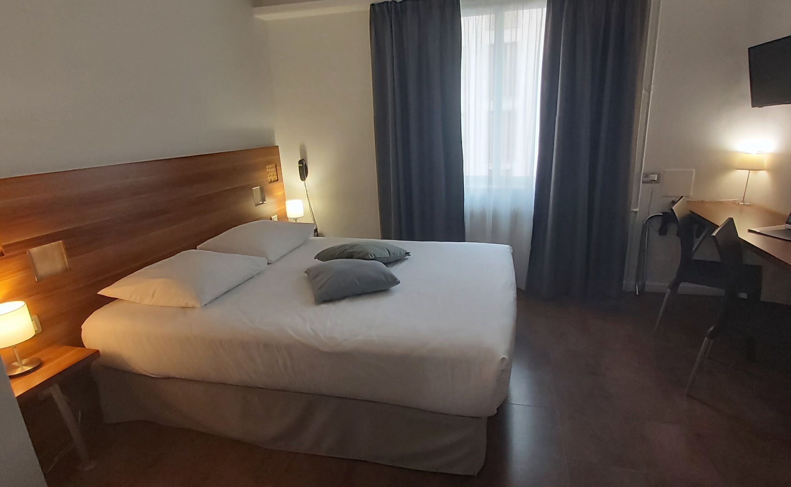 Une chambre d’hôtel avec un grand lit, un bureau et une chaise.