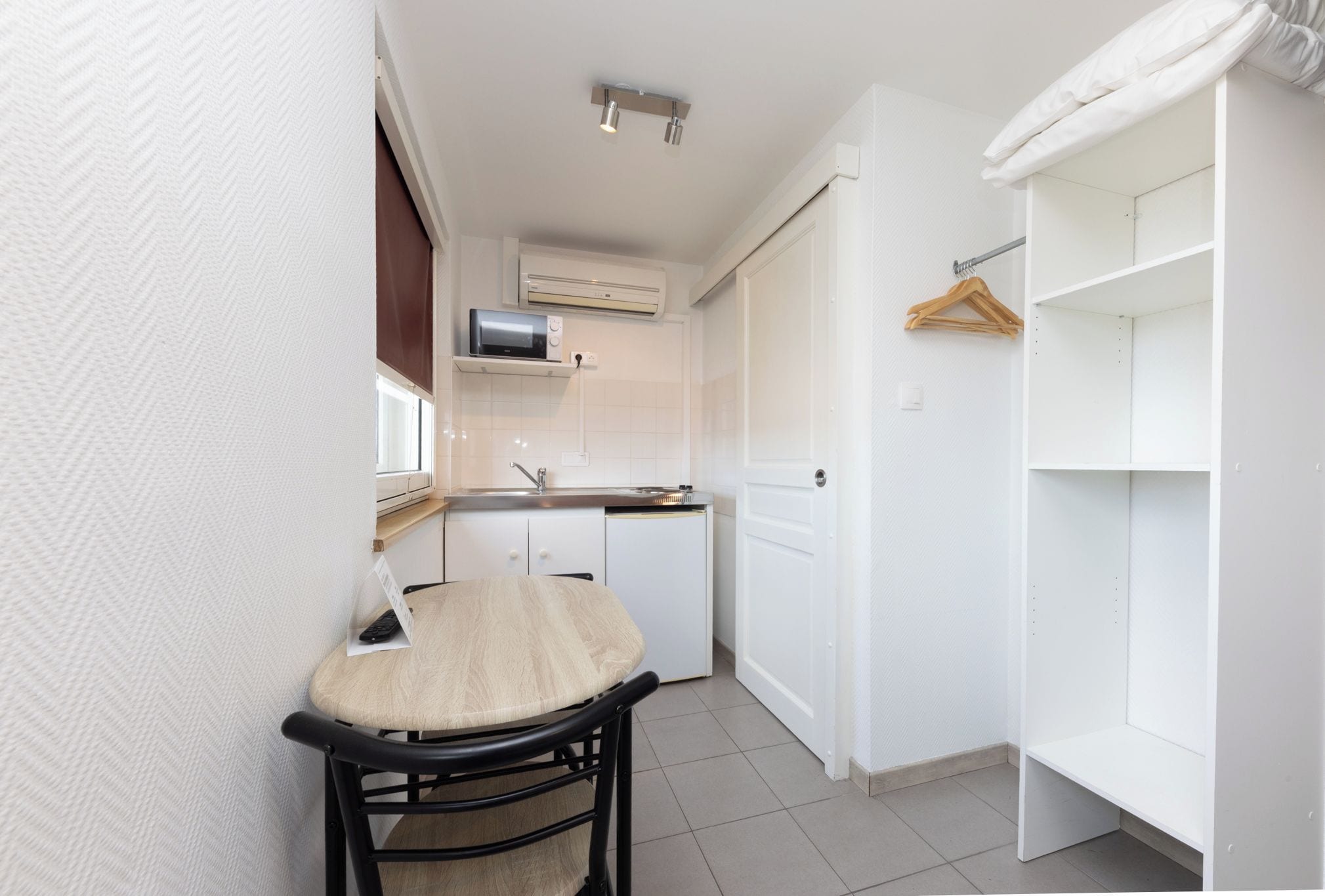 Una cocina compacta con comedor, un armario blanco y una percha para ropa.