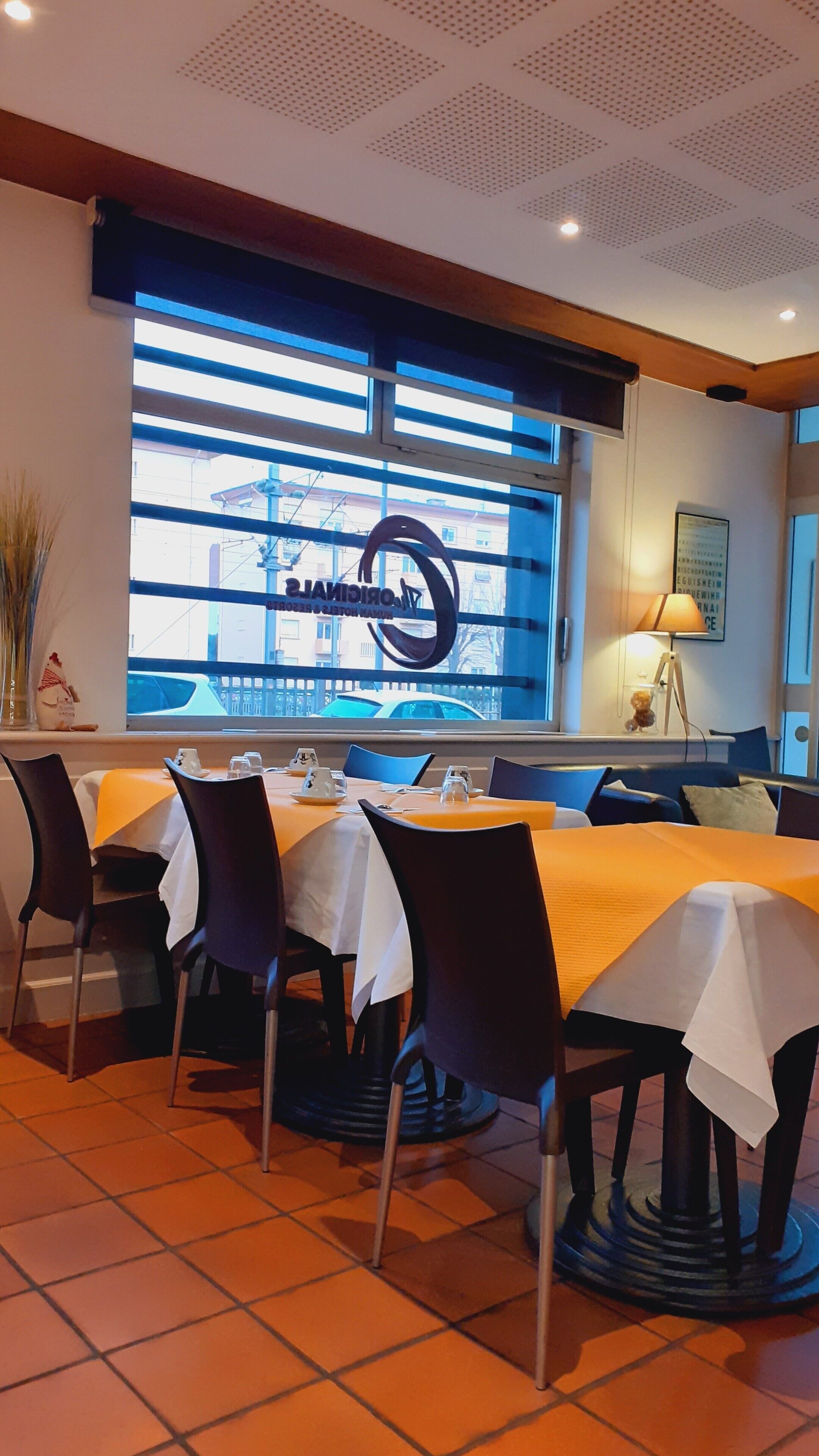 Ein Restaurant mit gedeckten Tischen, einem großen Fenster mit Blick und einer Decke mit einem außergewöhnlichen Muster.