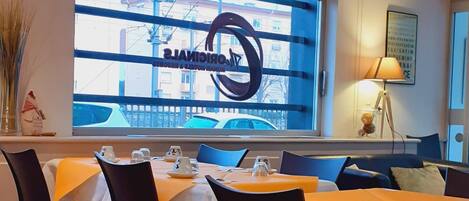 Ein Restaurant mit gedeckten Tischen, einem großen Fenster mit Blick und einer Decke mit einem außergewöhnlichen Muster.
