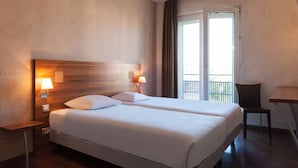 Une chambre d’hôtel avec deux lits, une table de chevet avec des lampes, une chaise et un balcon avec vue.