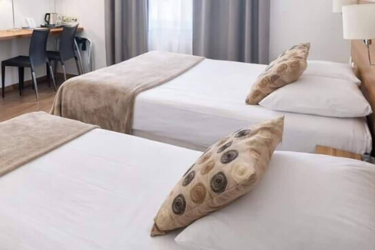 Habitación de hotel con dos camas, un escritorio y una silla.