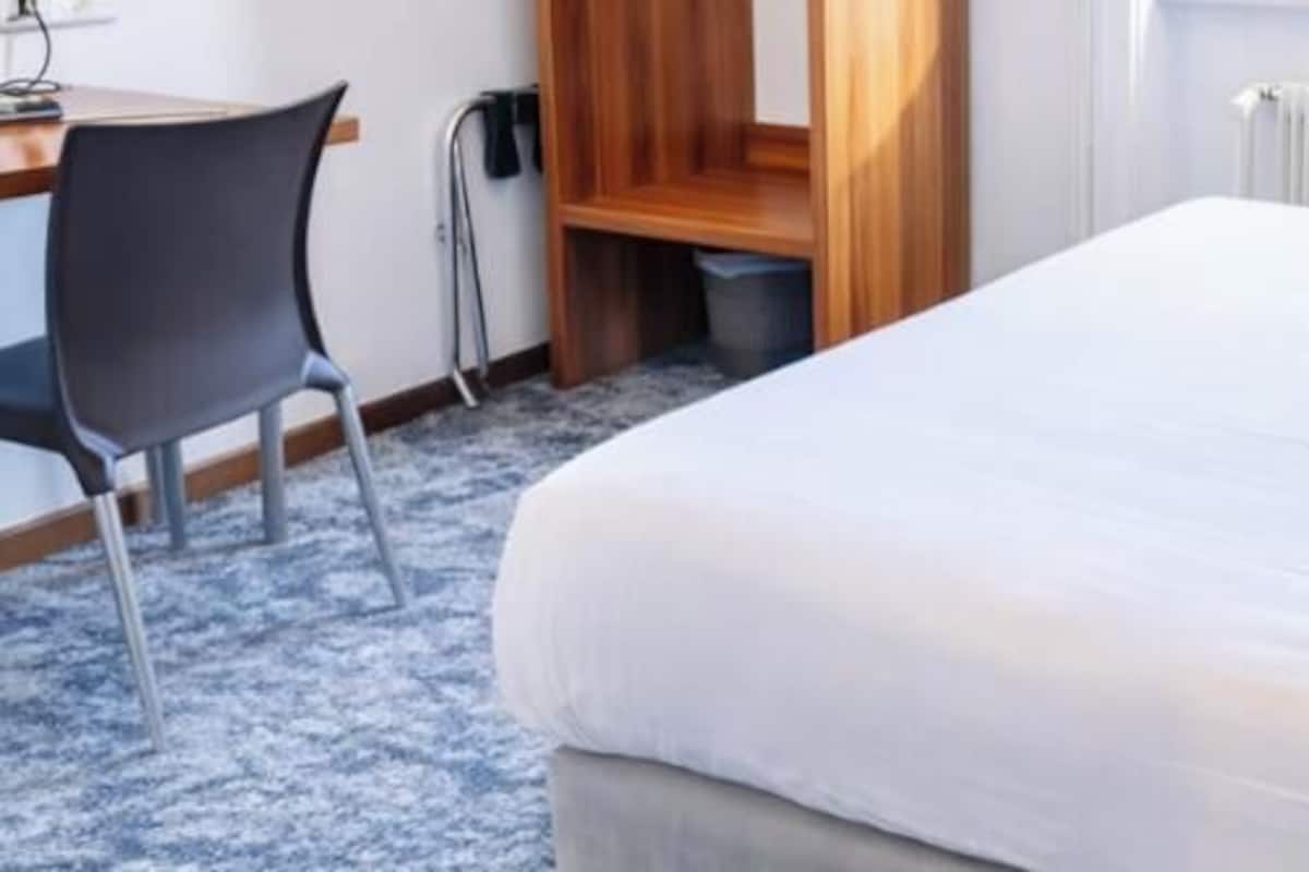 Una habitación de hotel con una cama, un escritorio y una silla.