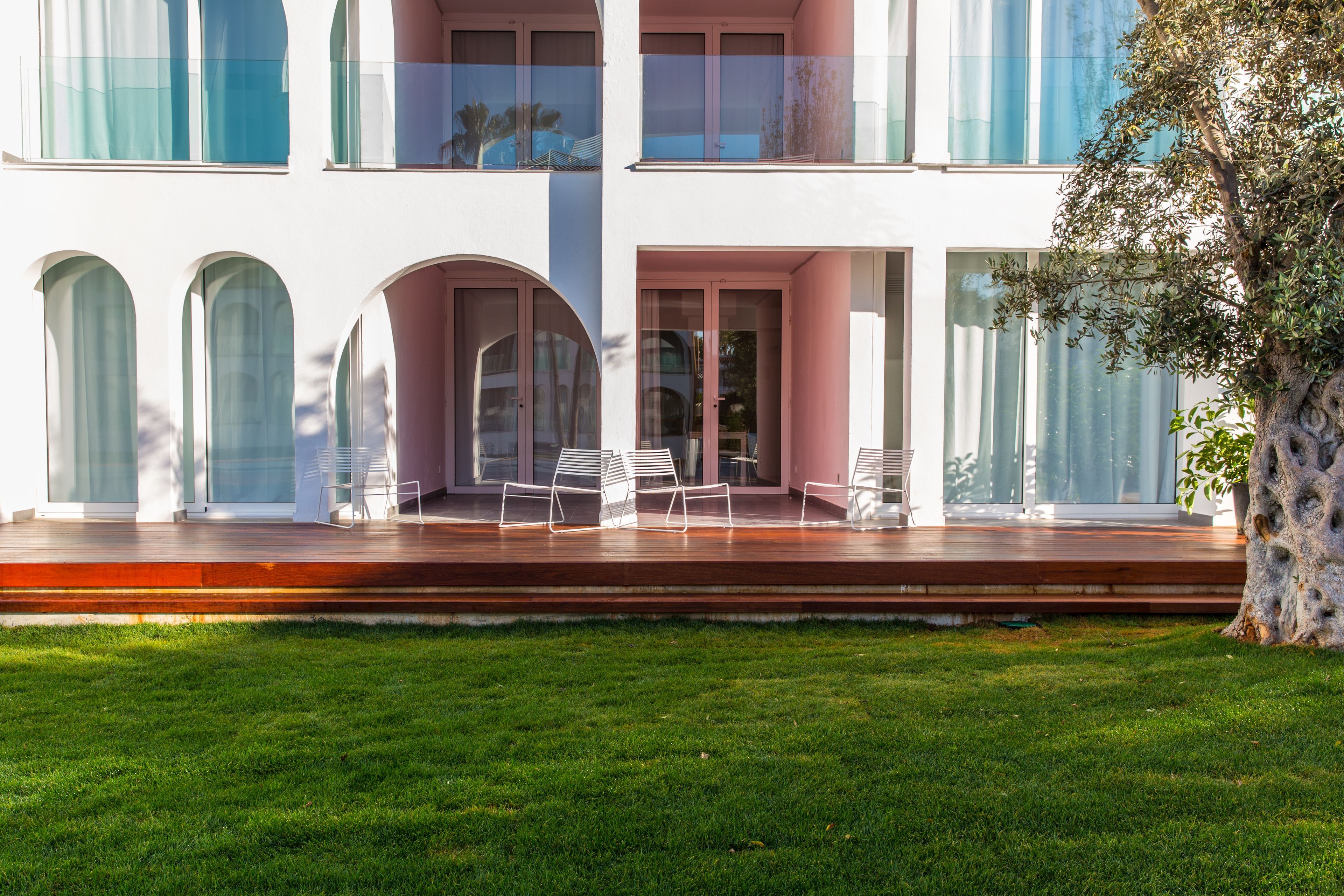 A modern two-story building with large windows, a wooden deck, and outdoor seating.