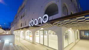 A modern building with a prominent 'ebano' sign, featuring a clean architectural design with arched windows and a covered walkway. - Ebano Hotel Apartments & Spa (Sant Josep de sa Talaia)