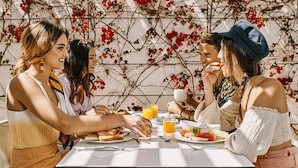 A group of people dining at a table with a floral backdrop. - Ebano Hotel Apartments & Spa (Sant Josep de sa Talaia)