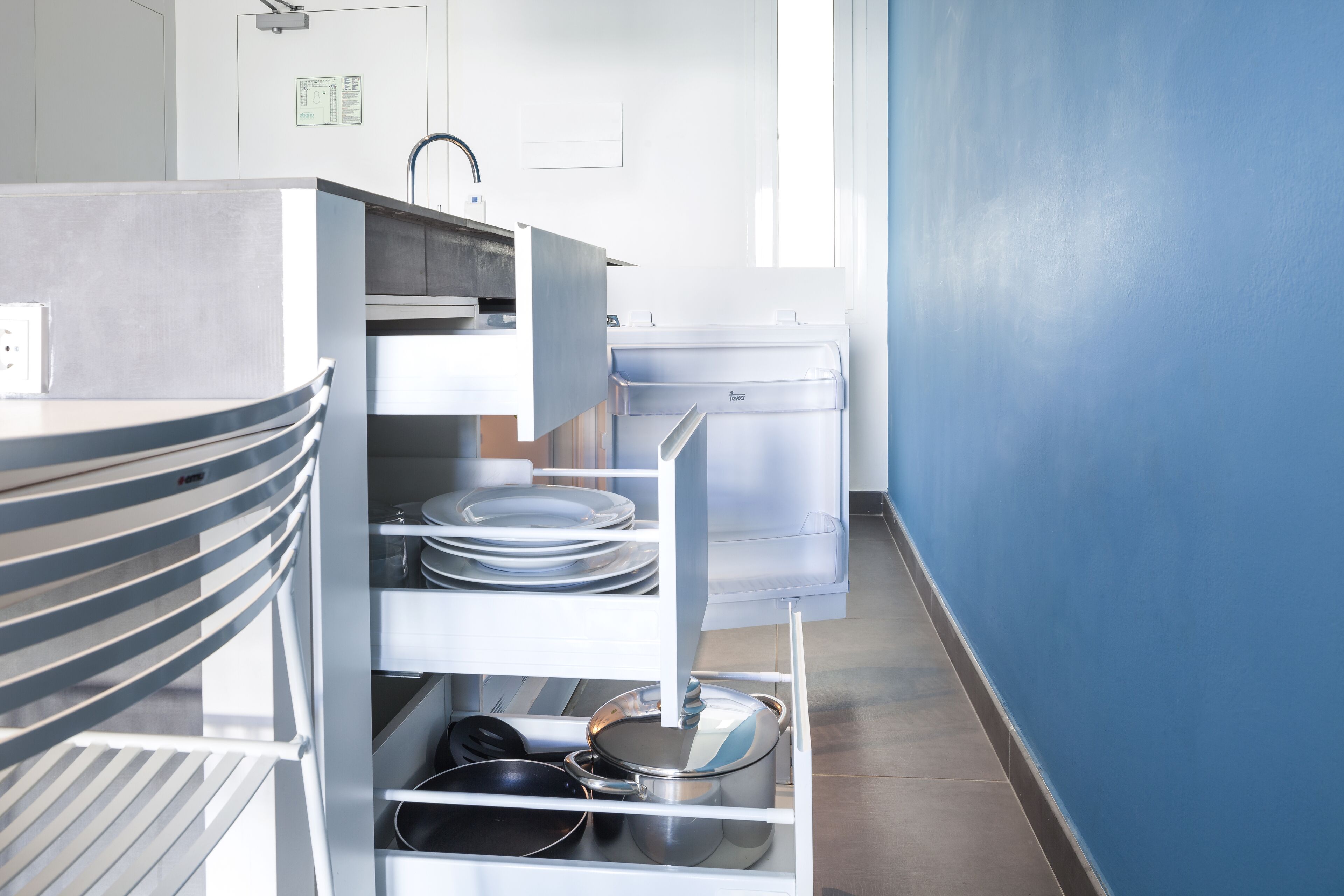Une cuisine équipée d’appareils électroménagers en acier inoxydable, d’un réfrigérateur blanc et d’un mur bleu.