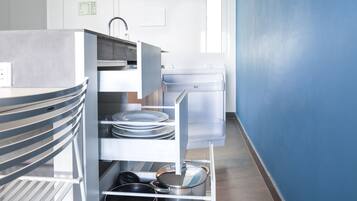 Une cuisine équipée d’appareils électroménagers en acier inoxydable, d’un réfrigérateur blanc et d’un mur bleu.