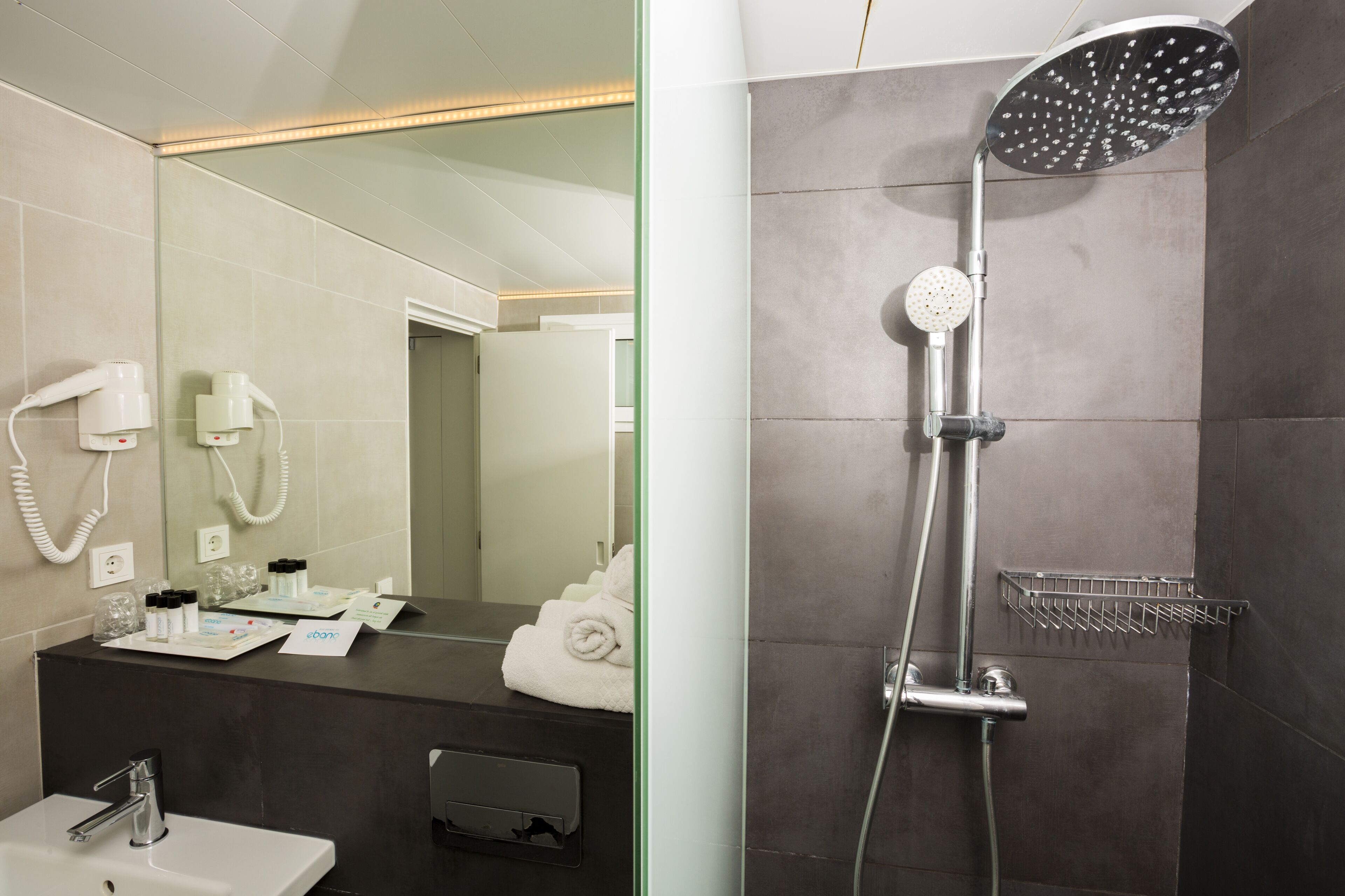 Un baño con lavabo, espejo, secador de pelo y ducha.