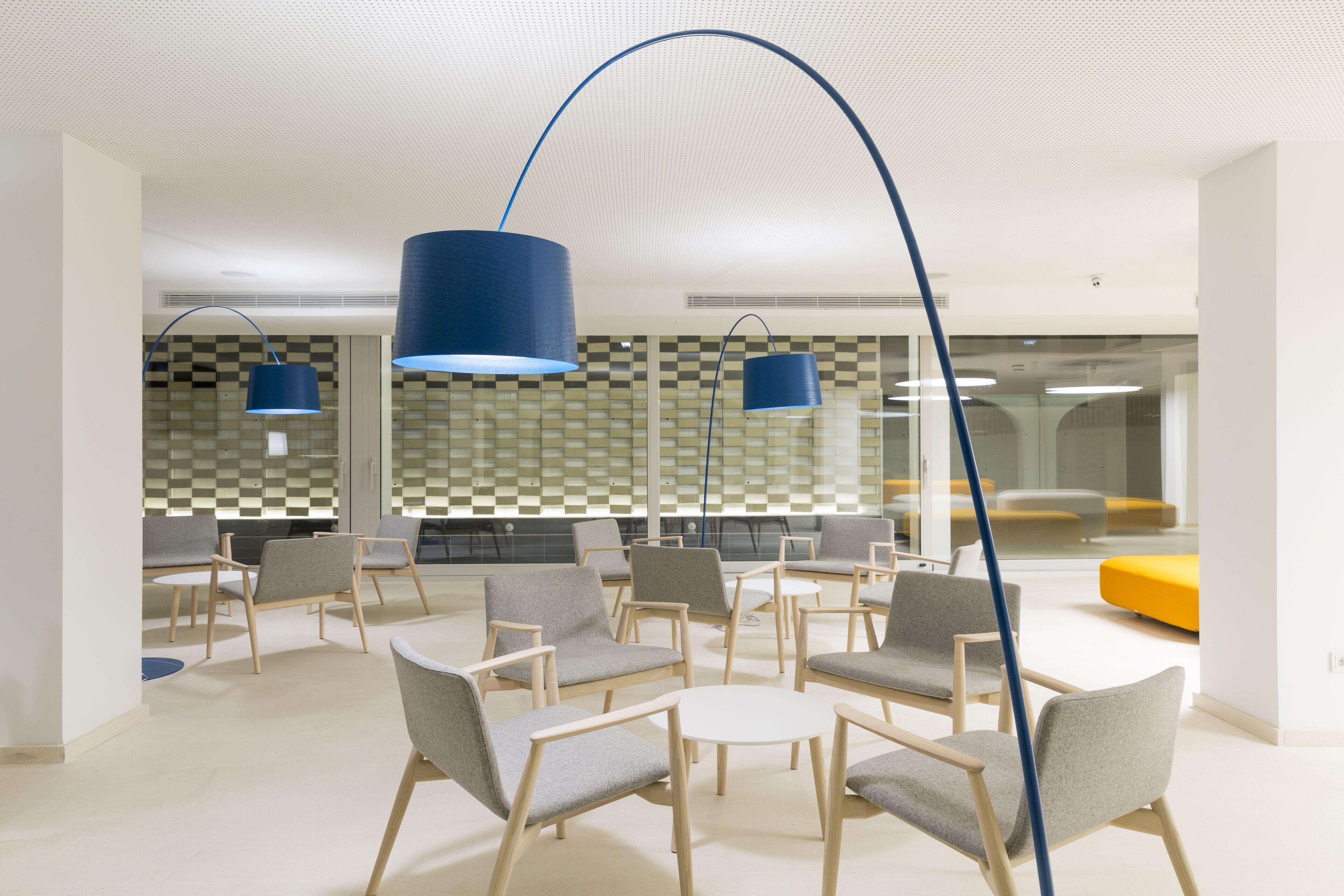 Un espace de détente moderne, doté de sièges et d’un éclairage suspendu bleu.