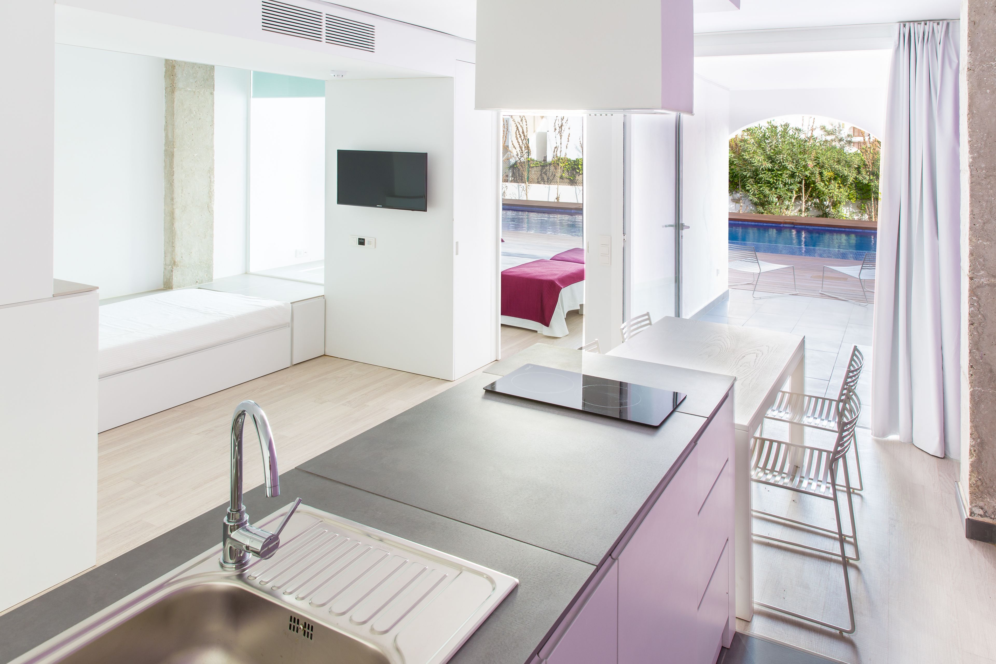 A modern kitchen with a built-in dishwasher, a large window, and a view of an outdoor pool area.