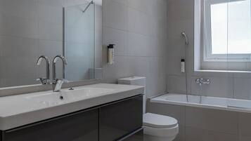 Un baño moderno con un espejo grande, dos lavamanos, un inodoro y una bañera.