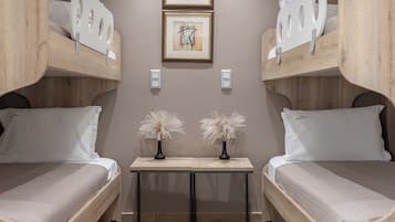 Une chambre avec deux lits superposés, une petite table ornée de deux vases et deux œuvres d’art encadrées accrochées au mur.