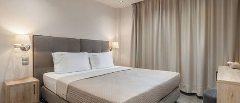 A hotel room with a bed, bedside tables, and a desk.
