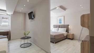 A modern bedroom with a bed, bedside tables, a TV mounted on the wall, and a window with blinds.