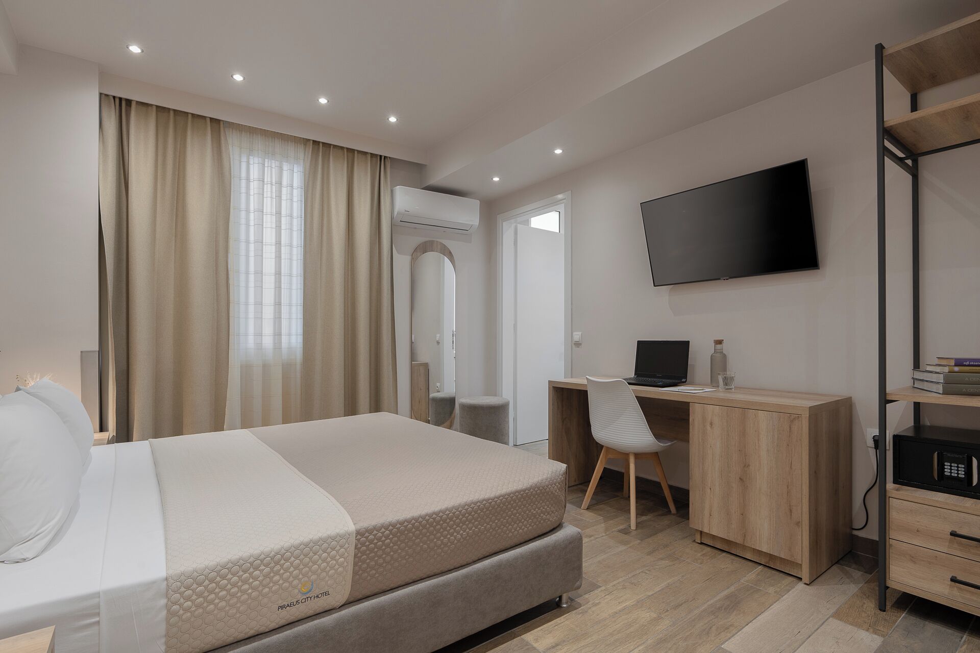 Una habitación de hotel moderna con cama, escritorio, silla, televisor y armario.
