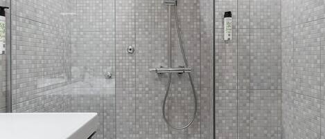 Un baño moderno con ducha envuelta en vidrio, inodoro blanco y tocador con espejo.