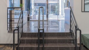 Un intérieur moderne avec une entrée en verre, des rampes en métal et un sol carrelé.
