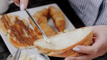 A person spreading butter on a slice of bread.