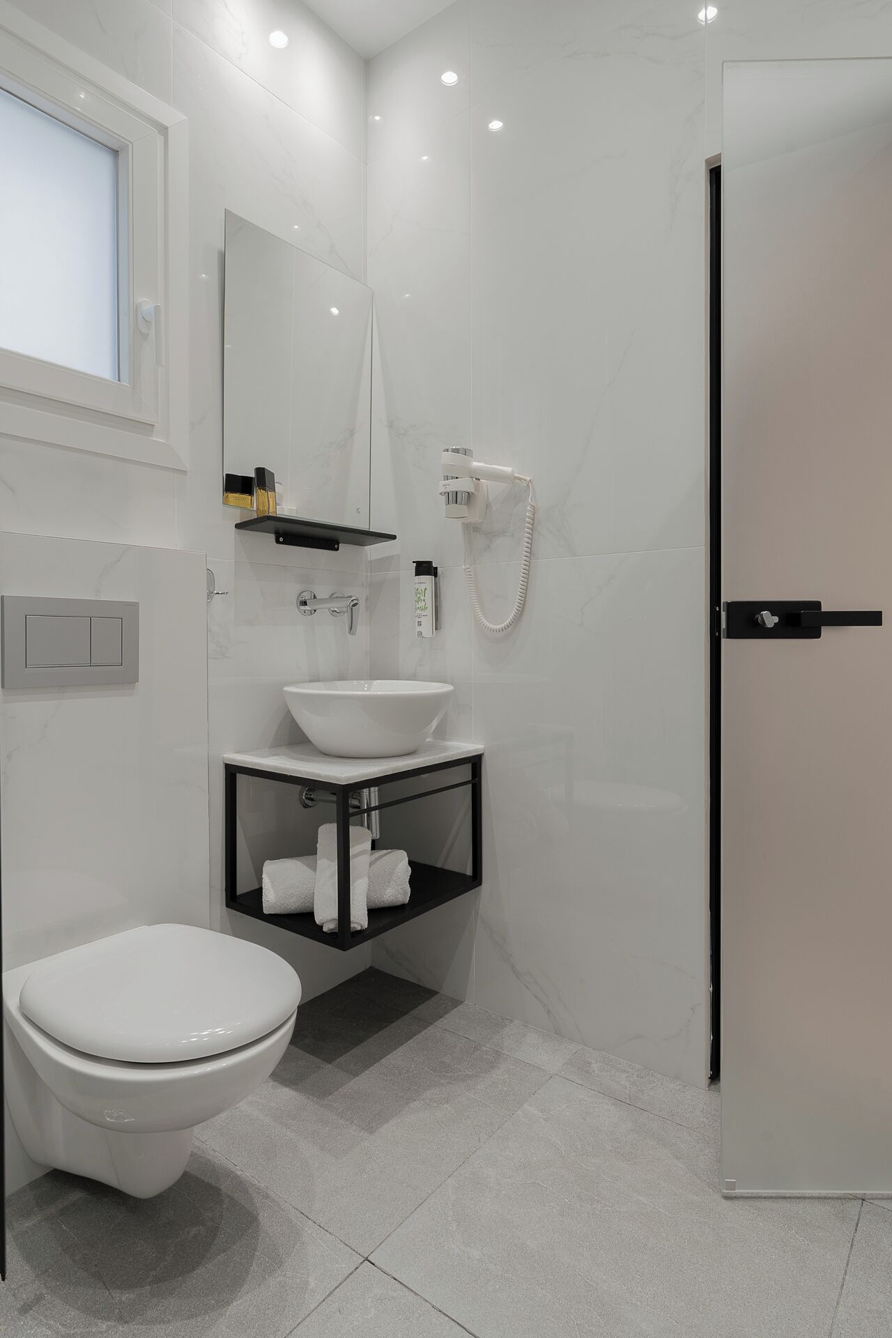 A modern bathroom with a white toilet, a sink with a black countertop, and a shower area.