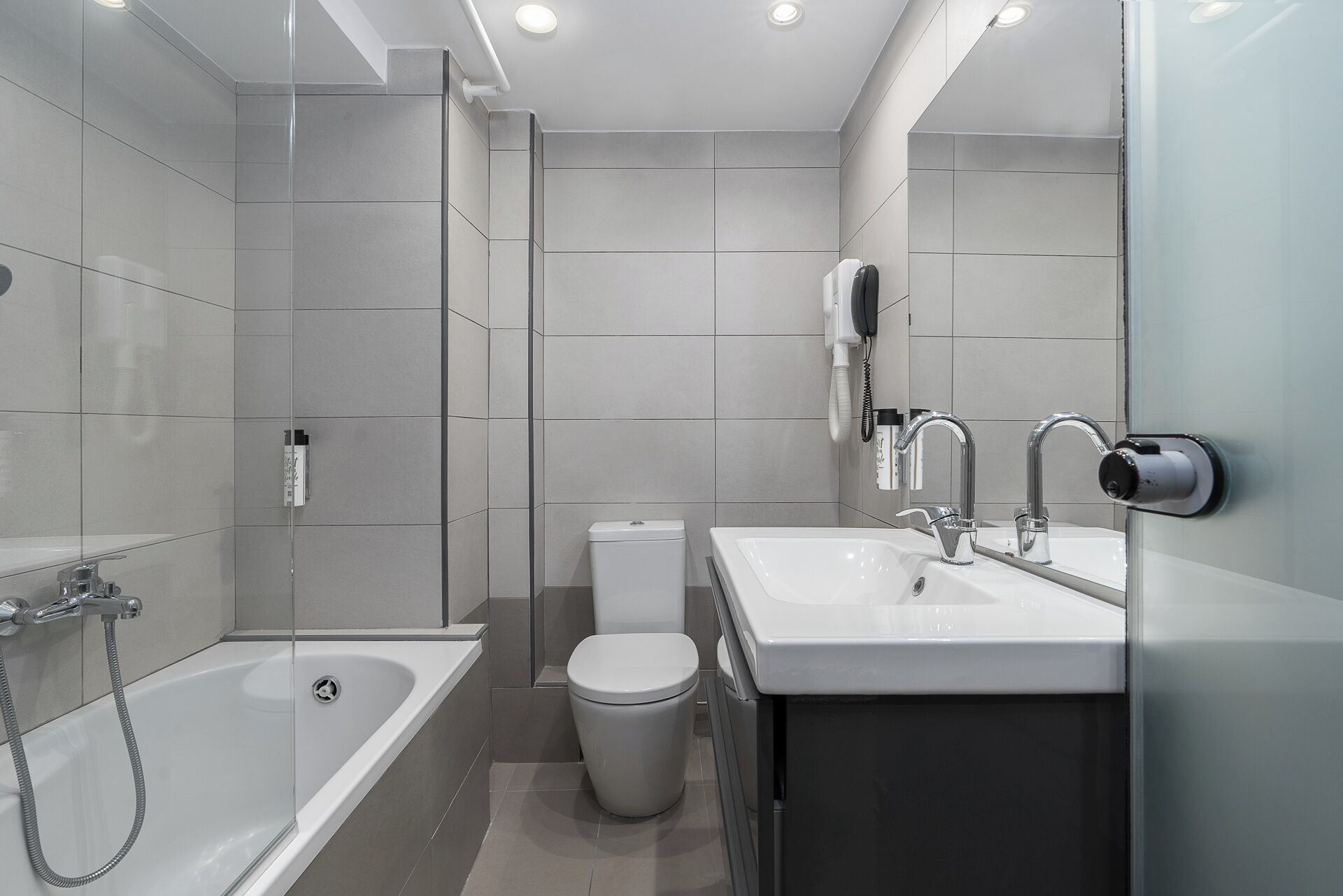 Een moderne badkamer met een bad, toilet en wastafel.