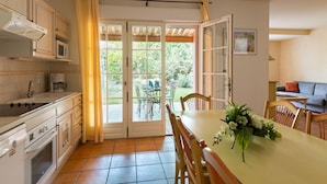 Een keuken met oven, magnetron en een eethoek met tafel en stoelen.