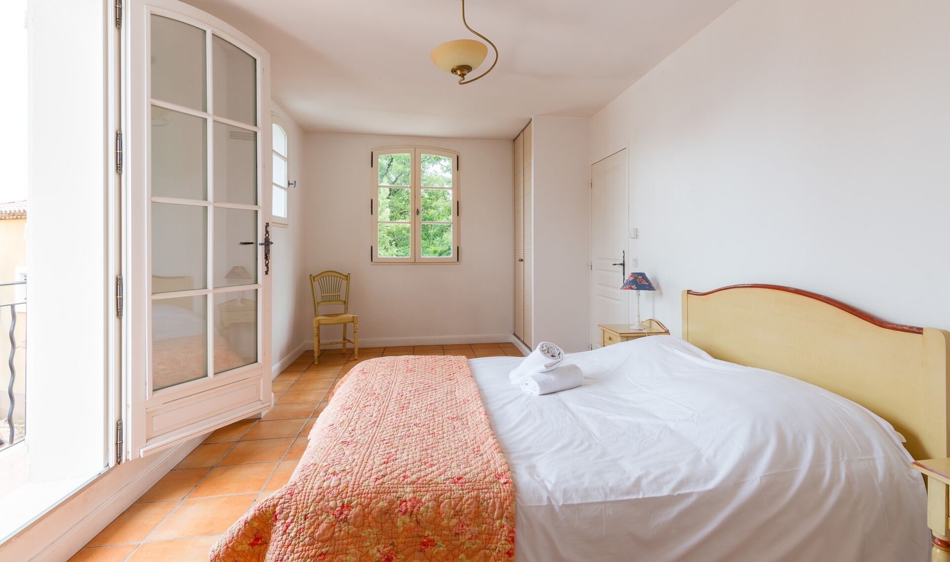 Een slaapkamer met een bed, een stoel, een raam en een deur.